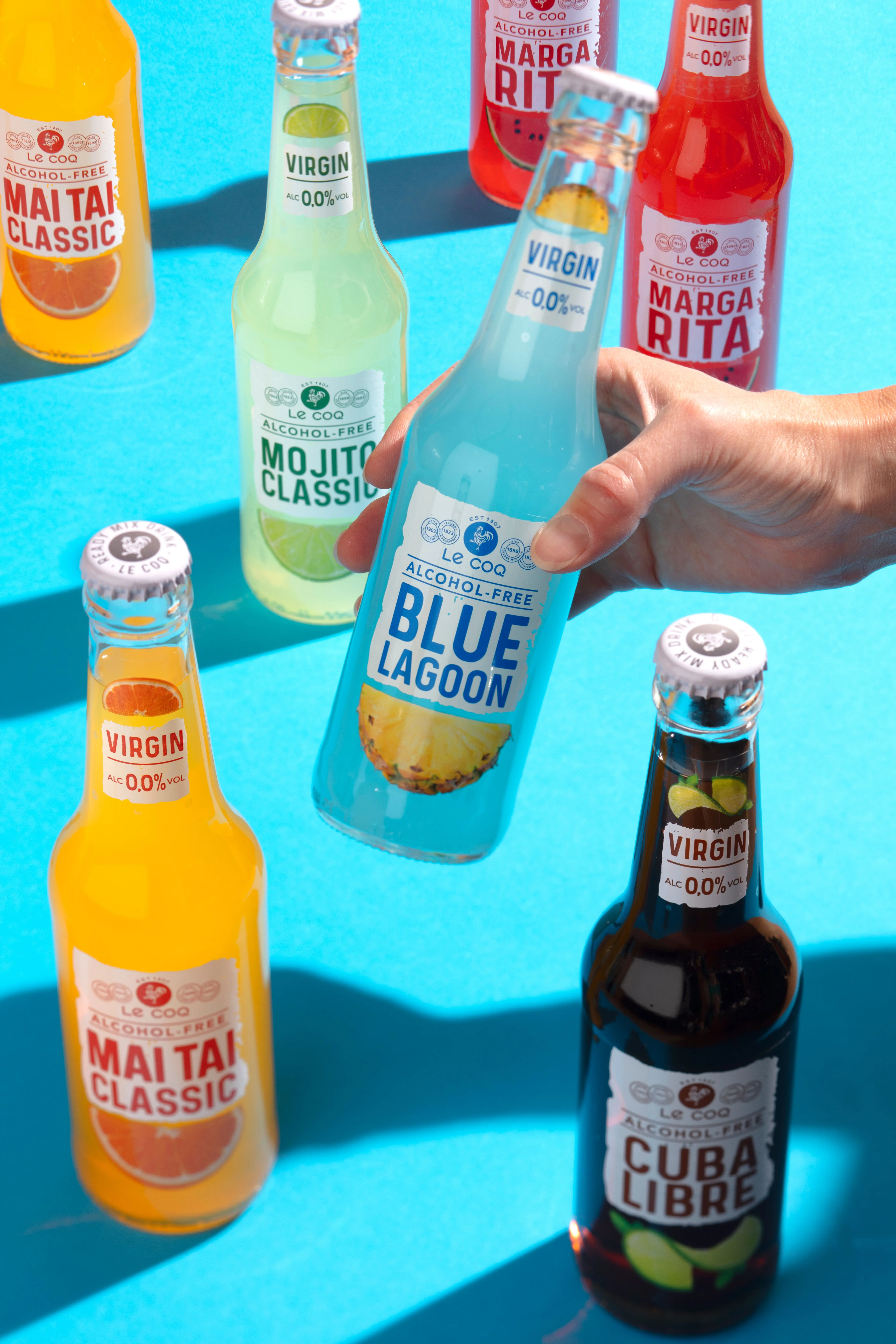 LeCoq_VIRGIN_bottles_on_blue_with_hand.jpg